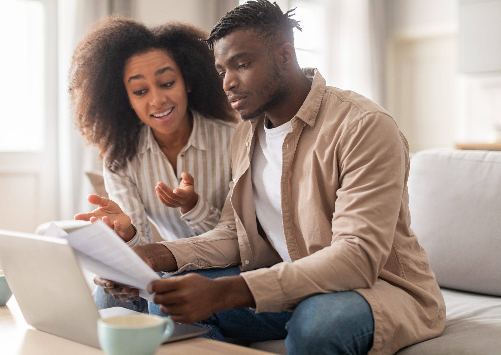 A couple sitting together with a laptop and paperwork, talking it through