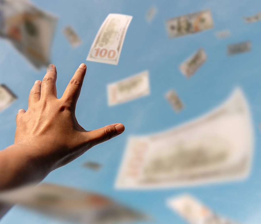A hand reaching up as banknotes fall through the air