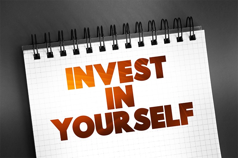 A notepad with the words Invest In Yourself written on it